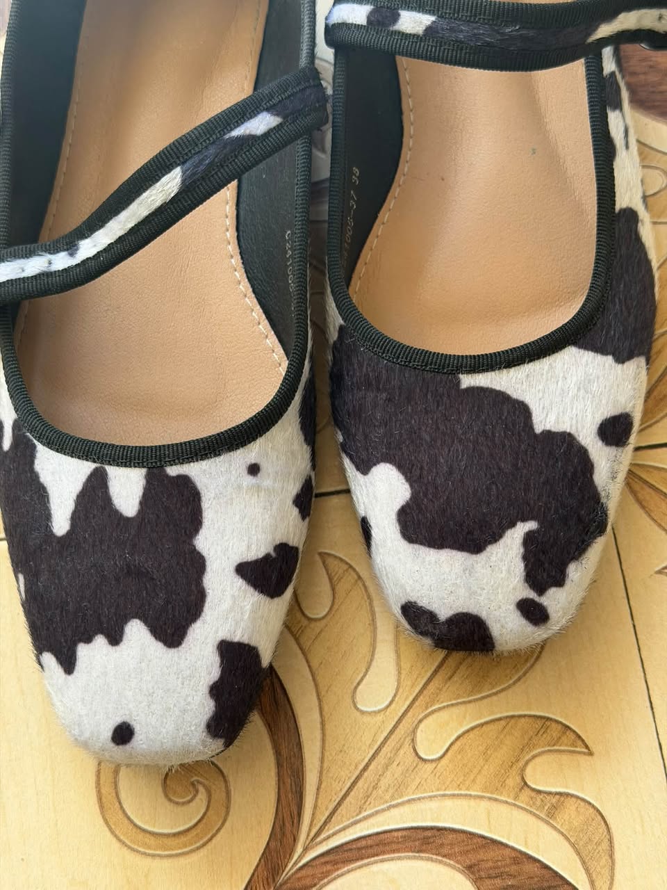 Cow-print ballet flats with ankle strap